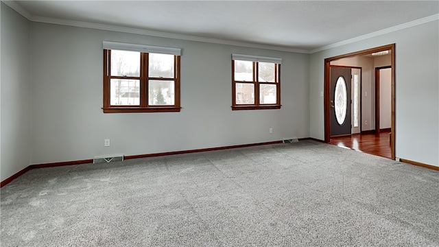 spare room featuring ornamental molding, carpet, visible vents, and baseboards