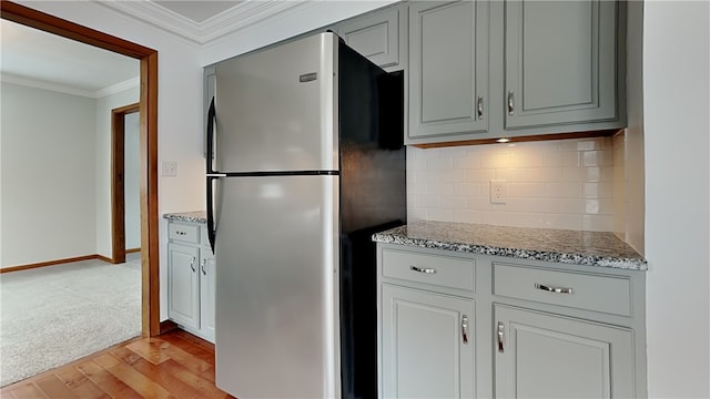 kitchen featuring gray cabinetry, backsplash, crown molding, and freestanding refrigerator