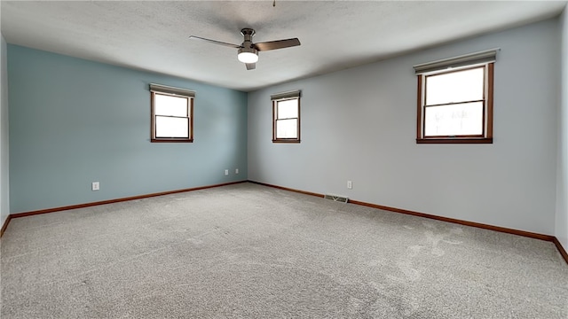 carpeted spare room with a textured ceiling, ceiling fan, visible vents, and baseboards