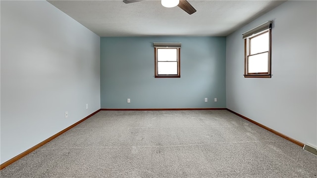 unfurnished room with carpet floors, ceiling fan, baseboards, and a textured ceiling