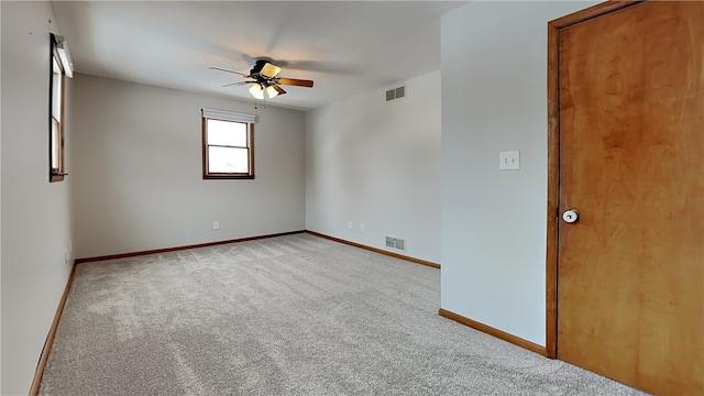 carpeted spare room featuring visible vents, ceiling fan, and baseboards