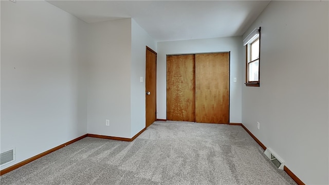 unfurnished bedroom with a closet, baseboards, visible vents, and carpet flooring