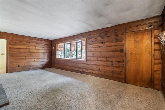 carpeted spare room featuring wood walls