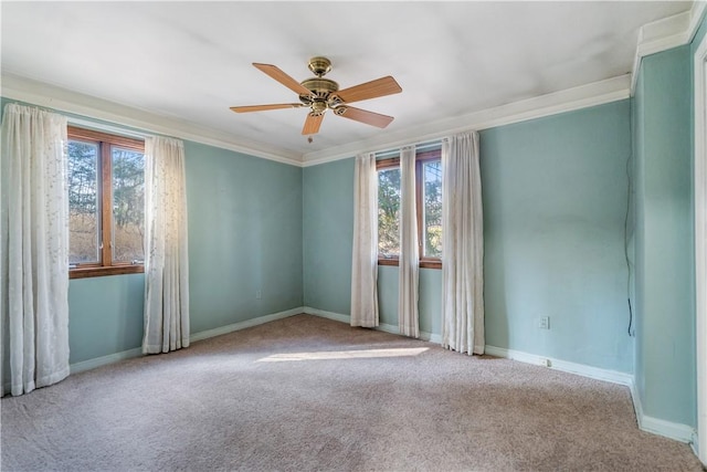 carpeted spare room featuring crown molding, baseboards, and ceiling fan