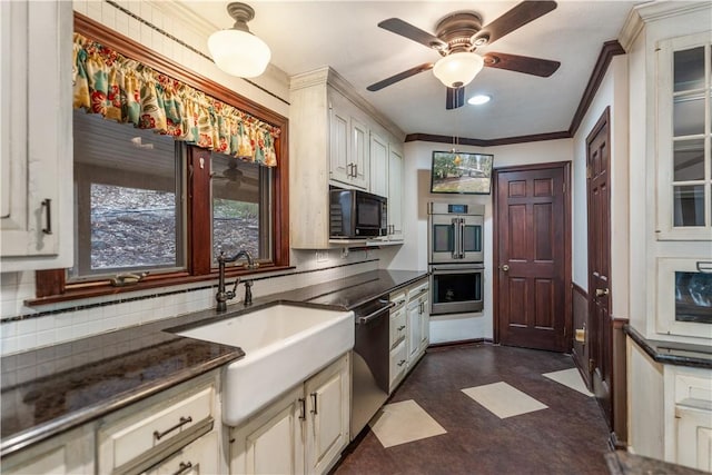 kitchen with stainless steel appliances, dark countertops, a sink, and dark floors