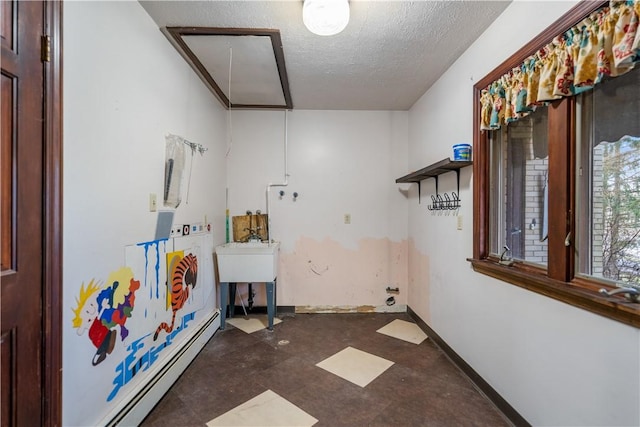 laundry area with attic access, baseboards, tile patterned floors, baseboard heating, and a textured ceiling