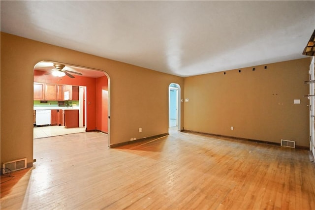 unfurnished living room with arched walkways, light wood-style flooring, and visible vents