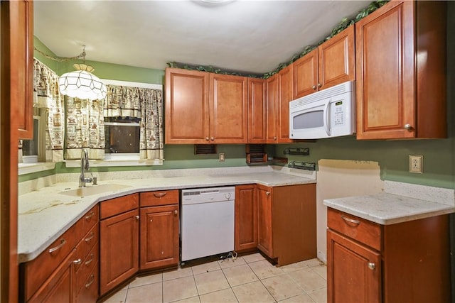 kitchen with light tile patterned floors, white appliances, a sink, and brown cabinets