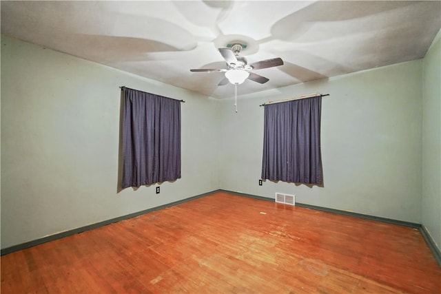 unfurnished room featuring baseboards, wood finished floors, visible vents, and a ceiling fan