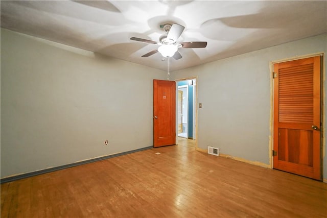 spare room featuring a ceiling fan, visible vents, and wood finished floors