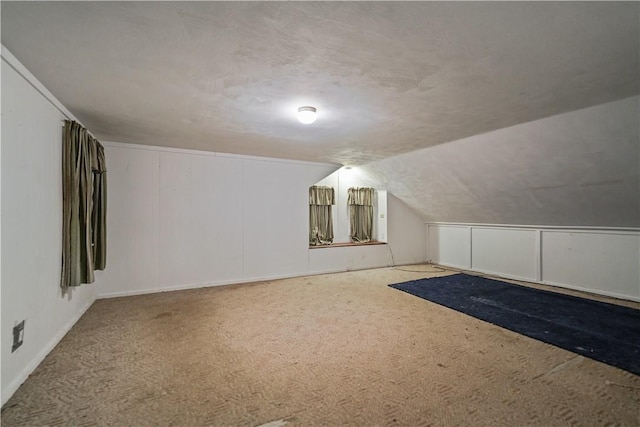 additional living space featuring vaulted ceiling, a textured ceiling, and carpet flooring