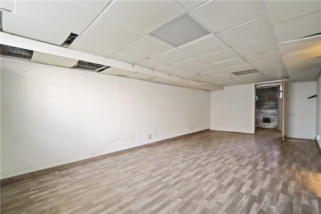 finished basement featuring a drop ceiling, baseboards, and wood finished floors