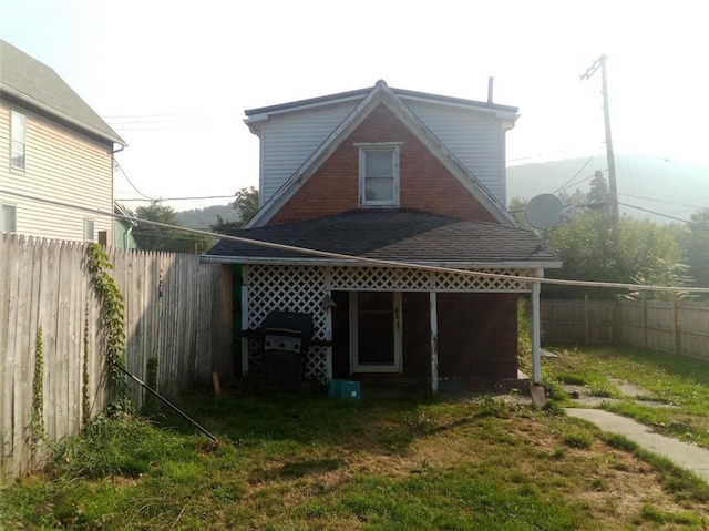 rear view of property with a fenced backyard and a yard