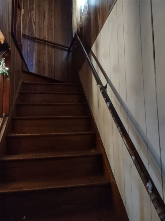 stairway featuring wooden walls