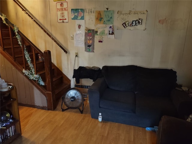 living room with stairs, wood walls, and wood finished floors