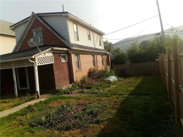 view of property exterior with a yard, brick siding, and fence