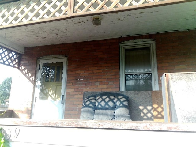 view of exterior entry with covered porch and brick siding