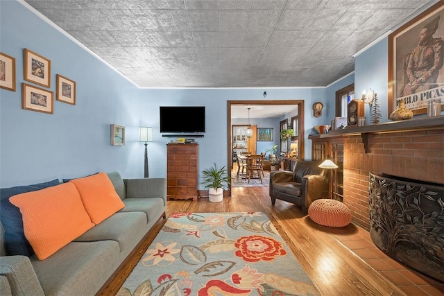 living area featuring ornamental molding, a fireplace, and wood finished floors