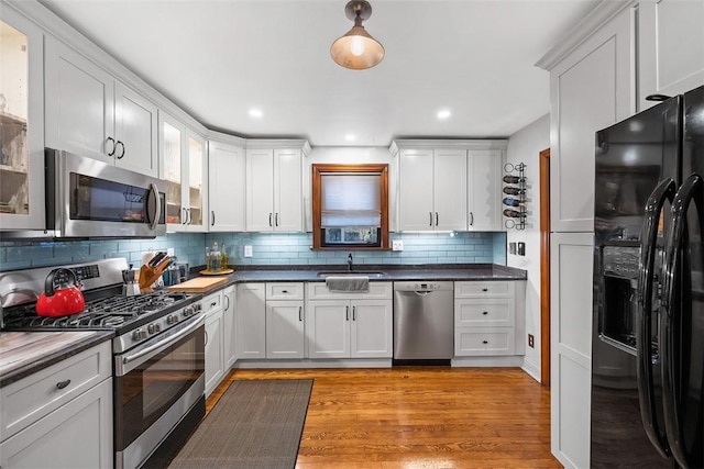 820 Mcdonald St, Sewickley, PA 15143 - kitchen featuring appliances with stainless steel finishes, tasteful backsplash, glass insert cabinets, light wood-style flooring, and white cabinets