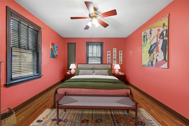 bedroom with a ceiling fan, baseboards, and wood finished floors