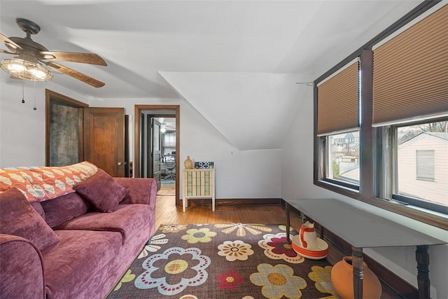 living area featuring light wood-style floors, baseboards, and vaulted ceiling