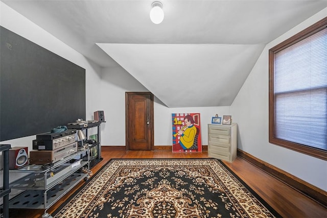 interior space with baseboards, vaulted ceiling, and wood finished floors