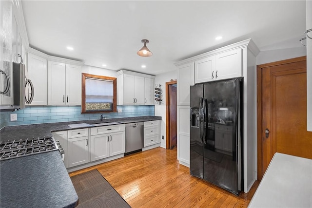 kitchen with stainless steel appliances, a sink, white cabinets, and light wood-style floors