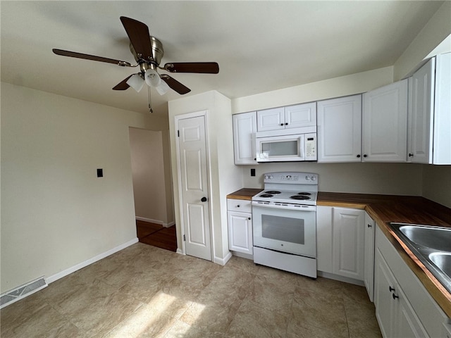 kitchen featuring white appliances, visible vents, white cabinets, butcher block counters, and a sink