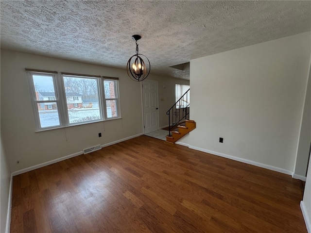 interior space with baseboards, visible vents, wood finished floors, stairs, and a notable chandelier