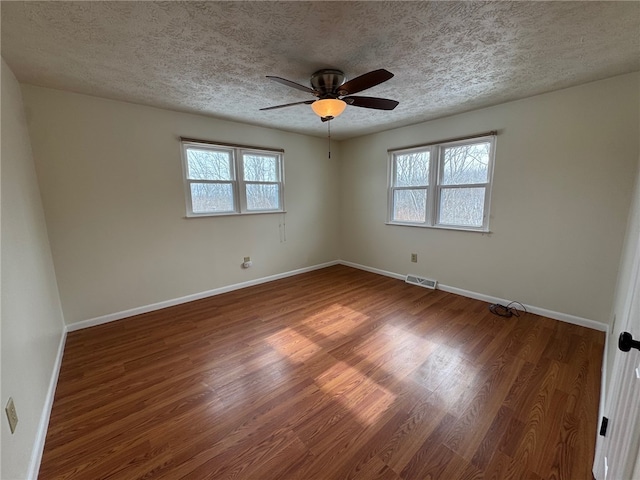 empty room with visible vents, baseboards, and wood finished floors