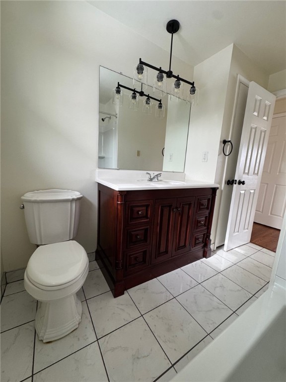 bathroom with toilet, marble finish floor, and vanity