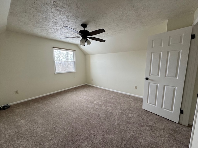 carpeted empty room with lofted ceiling, ceiling fan, a textured ceiling, and baseboards