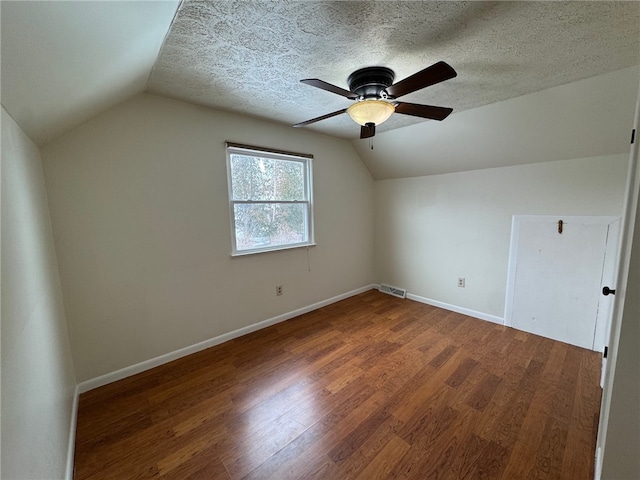 bonus room featuring visible vents, baseboards, lofted ceiling, wood finished floors, and a textured ceiling