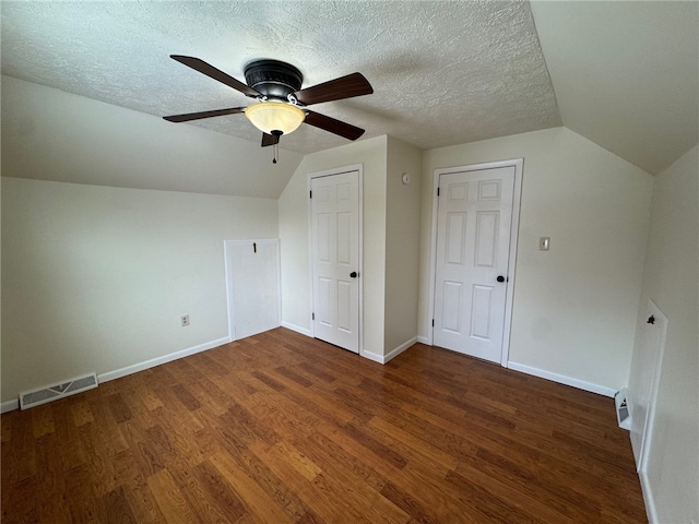 additional living space with lofted ceiling, a textured ceiling, wood finished floors, visible vents, and baseboards