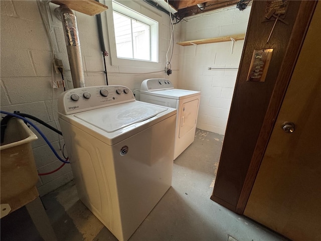 washroom featuring laundry area, separate washer and dryer, and concrete block wall