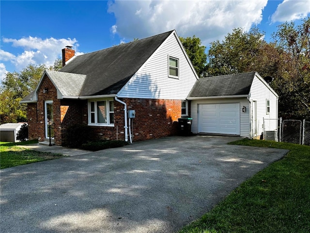 view of home's exterior featuring aphalt driveway, brick siding, a chimney, an attached garage, and fence