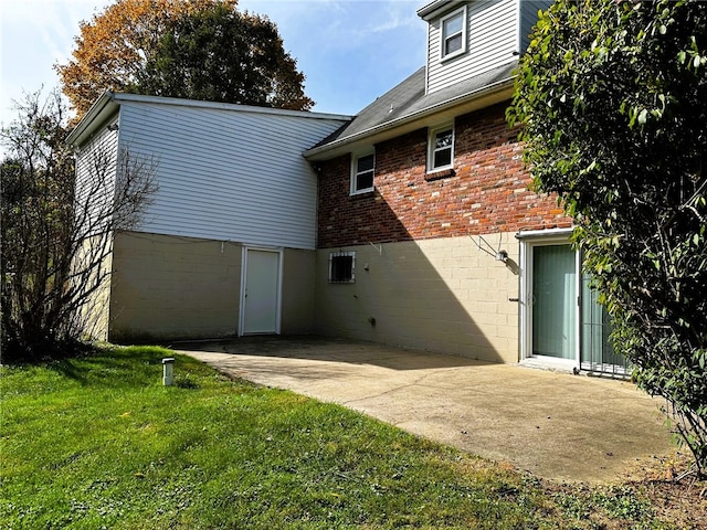 back of property featuring a yard, a patio area, and brick siding