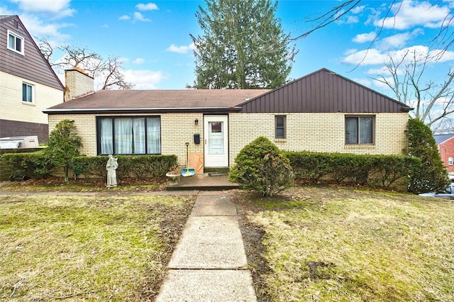 ranch-style home with a front yard, brick siding, and a chimney