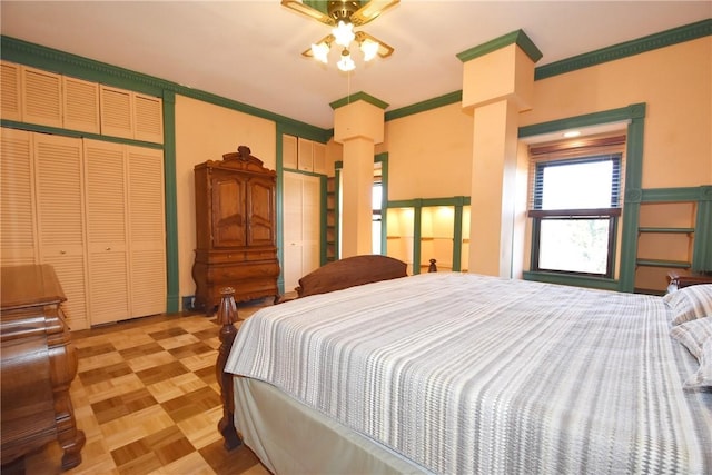 bedroom featuring ornate columns, multiple closets, and crown molding