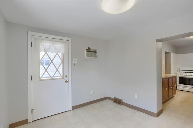 foyer with a wall unit AC, light floors, visible vents, and baseboards