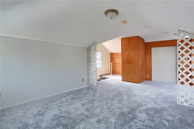 additional living space featuring wooden walls, carpet flooring, and lofted ceiling