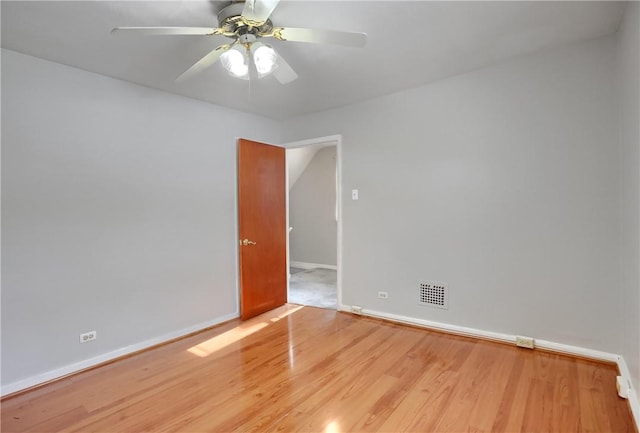 unfurnished room with visible vents, baseboards, wood finished floors, and a ceiling fan