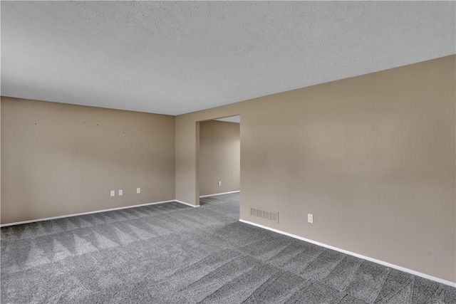 unfurnished room with dark colored carpet, visible vents, a textured ceiling, and baseboards