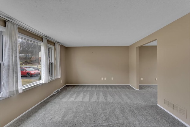 carpeted spare room with a textured ceiling, visible vents, and baseboards