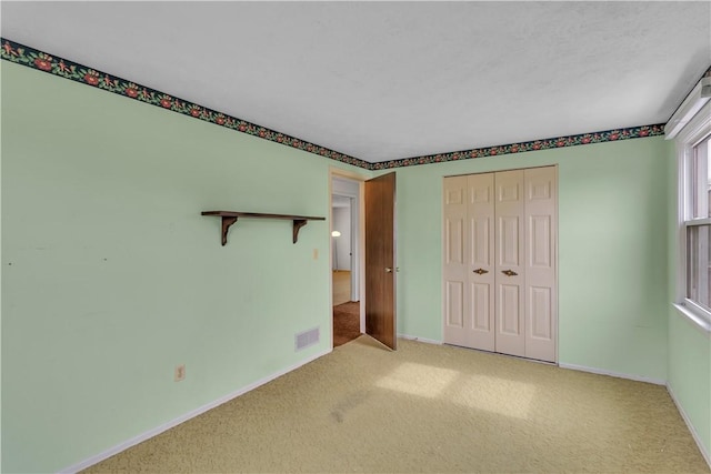 unfurnished bedroom featuring carpet, a closet, visible vents, and baseboards