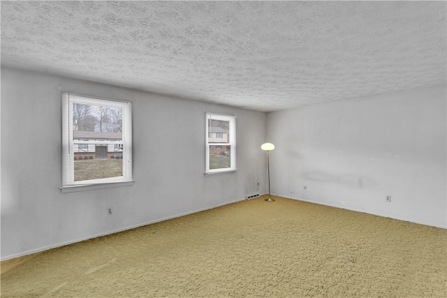 carpeted spare room featuring visible vents and a textured ceiling