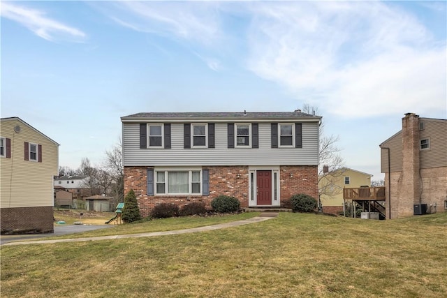 colonial house featuring brick siding, a front lawn, and central air condition unit