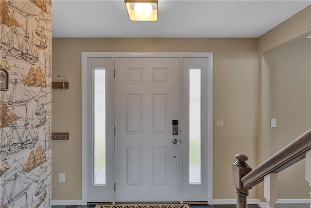 entryway featuring stairs, a wealth of natural light, and baseboards