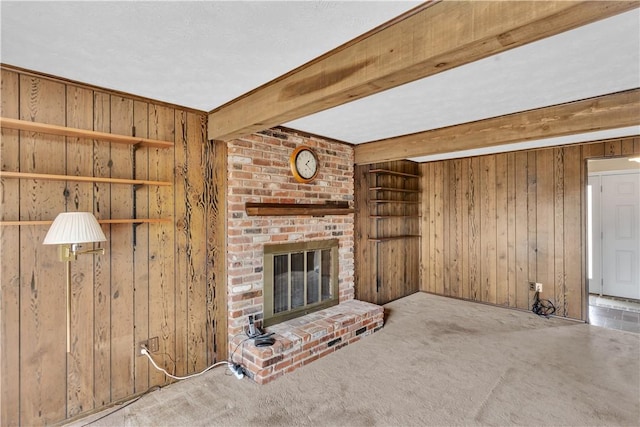 unfurnished living room featuring a brick fireplace, carpet, wooden walls, and beamed ceiling