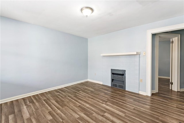 unfurnished living room with a fireplace, baseboards, and wood finished floors